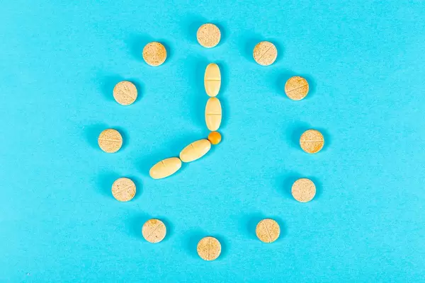 Clock from tablets on a blue background, top view