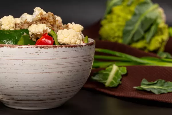 Close-up, a bowl of buckwheat porridge with vegetables on a dark background