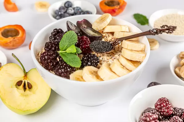 Close-up, a bowl of oatmeal with banana, berries and black sesame seeds