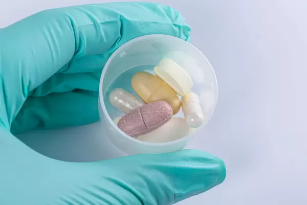 Close-up, a hand in a glove holds a dose of medicines