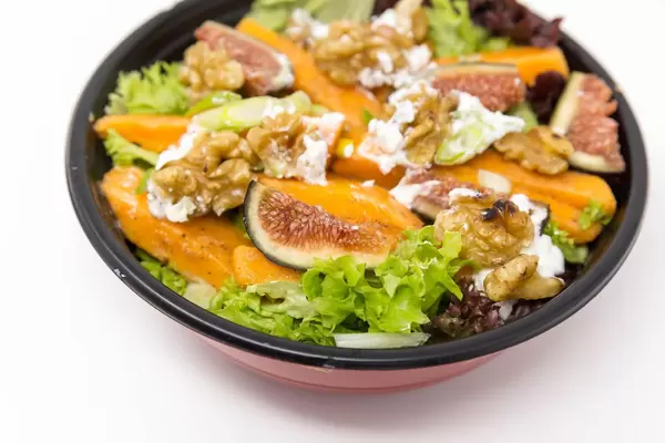 Close up -  A salat with figs, pumpkin, walnuts and cream cheese in a black bowl