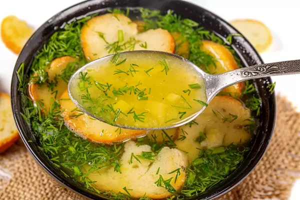 Close-up, a spoonful of potato soup with croutons and herbs