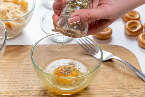 Close up adding spices to egg bowl