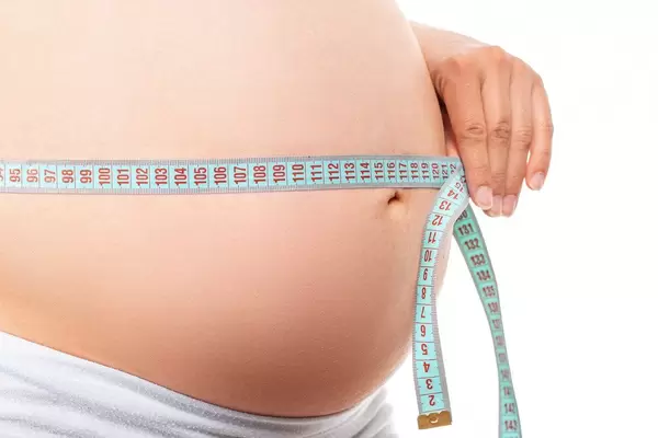 Close-up, big pregnant belly with measuring tape