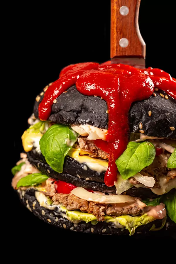 Close-up, black burger with a knife and a spicy red sauce