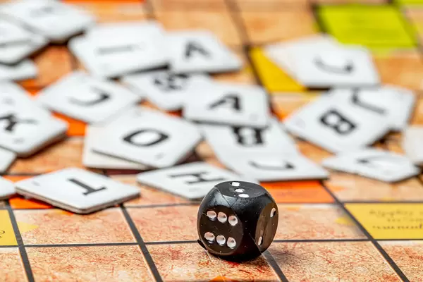 Close-up, black cube with numbers and letters behind it, the concept of the game of scrabble