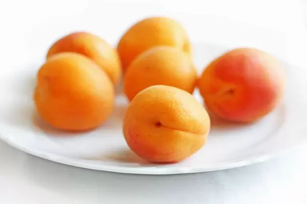 Close Up Bokeh Photo of Apricots on a White Plate