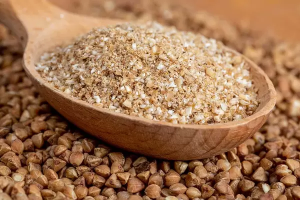 Close-up, buckwheat flour in a wooden spoon on the background of buckwheat