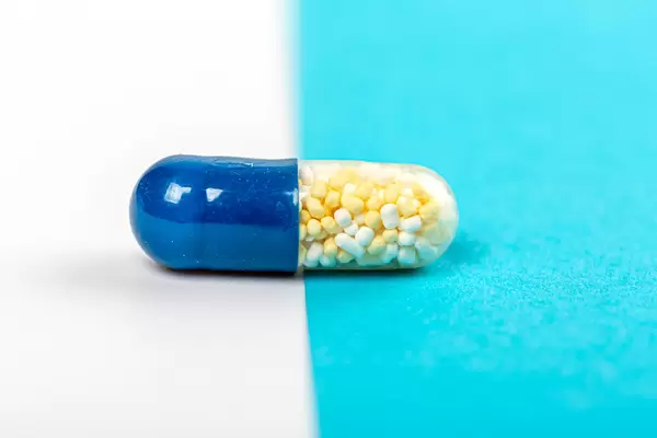 Close-up, capsule with medical granules inside on blue and white background