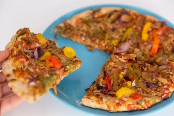 Close up crispy vegetarian Pizza in a hand and ready to eat