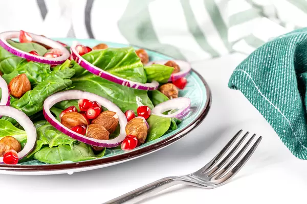Close-up dietary salad with hazelnuts, spinach, onions and pomegranate