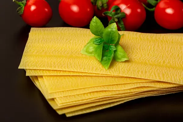 Close-up, dry lasagna sheets with basil and tomatoes