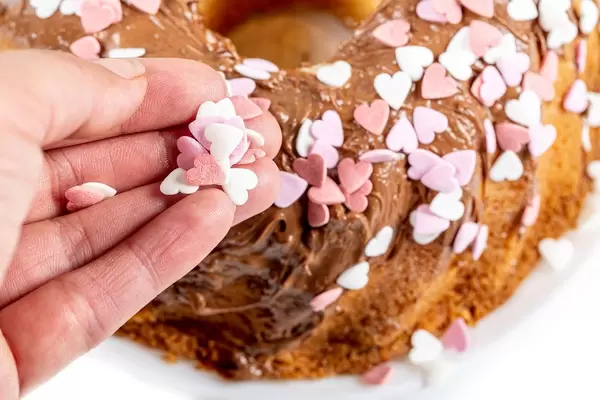 Close-up, female hand sprinkles hearts on a cupcake