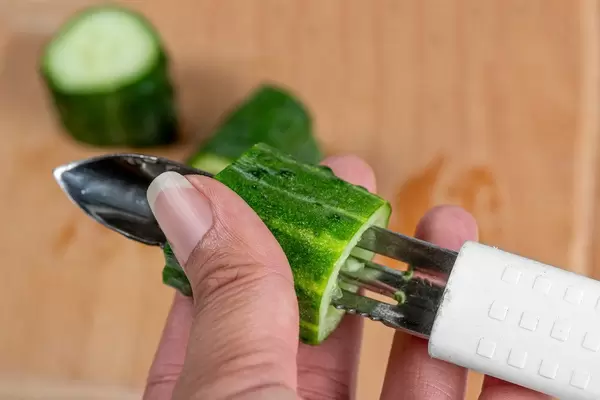 Close-up, female hands cut the pulp from a cucumber