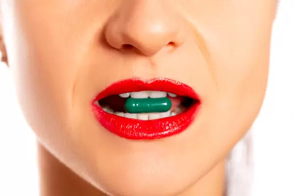 Close-up, female mouth with green capsule