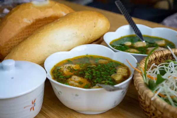 Close Up Food Photo of Bowl of Meatballs in Sauce with Baguette in the Background