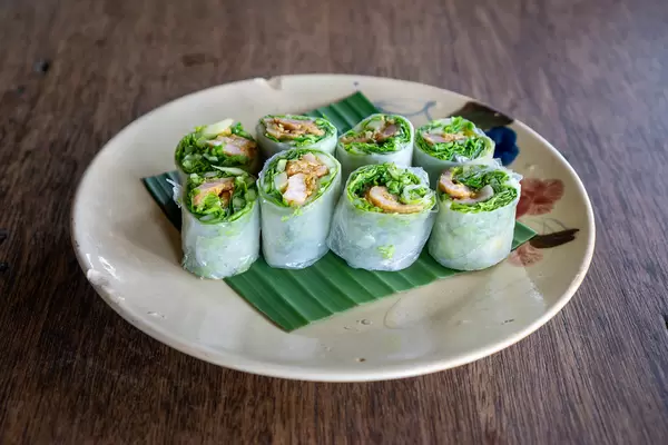 Close Up Food Photo of Fresh Spring Rolls with Grilled Pork and Herbs on a Banana Leaf in a Vietnamese Restaurant