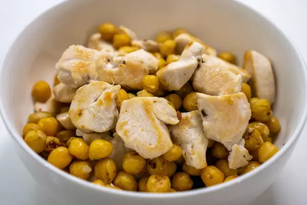 Close Up Food Photo of Grilled Chicken Breast with Fried Chickpeas in a White Ceramic Bowl