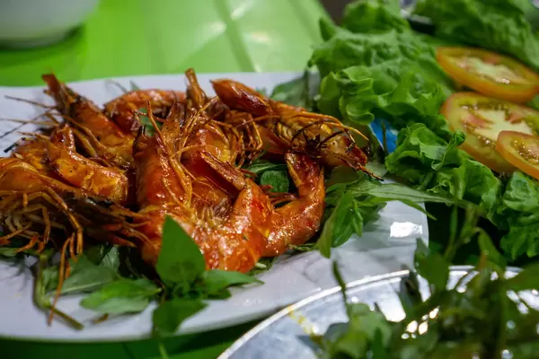 Close Up Food Photo of Grilled Shrimps with Chili and Lemongrass on Herbs at a Street Food Restaurant at a Night Market in Vietnam
