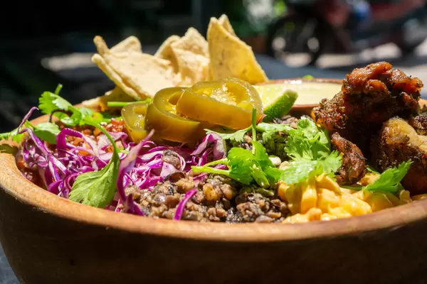 Close Up Food Photo of Healthy Bowl with Red Beans, Corn, Grilled Chicken, Cabbage, Jalapenos, Herbs, Tortilla Chips and Sauce in a Wooden Bowl