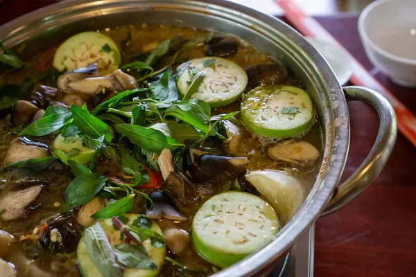 Close Up Food Photo of Hot Pot with Fremented Fish, Mushrooms, Eggplant and Fresh Herbs in a Vietnamese Restaurant