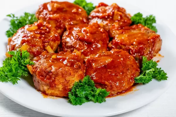 Close Up Food Photo of Meatballs with Tomato Sauce and Parsley on White Plate