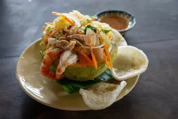 Close Up Food Photo of Pomelo Salad with Shrimps, Carrots, Peanuts, Pork, Shrimp Chips and Fish Sauce with Chili in a Vietnamese Restaurant