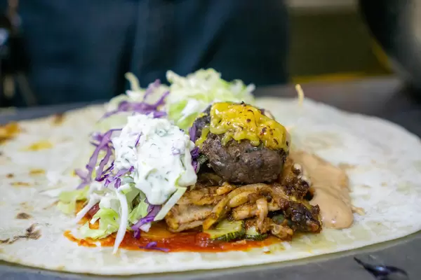 Close Up Food Photo of Preparation of Doner Durum Kebab Roll with Grilled Lamb Meat, Vegetables, Tzatziki, Cocktail Sauce and Cheese