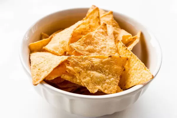 Close Up Food Photo of Seasoned Tortilla Cheese Chips in White Ceramic Bowl on White Background