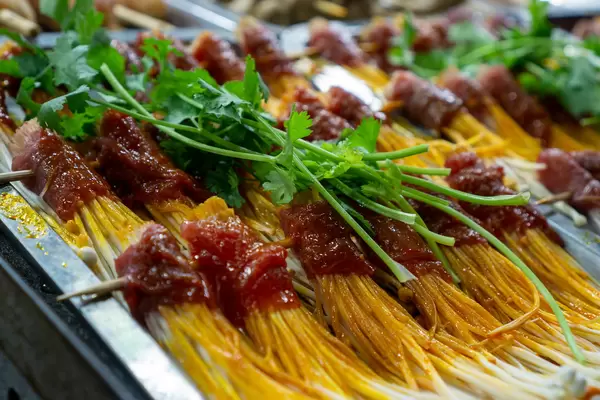 Close Up Food Photo of Skewers of Enoki Mushrooms wrapped in raw and marinated Beef for Barbecue topped with fresh Parsley