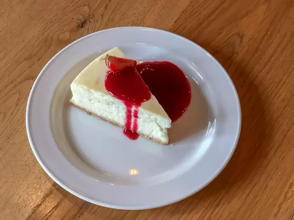 Close Up Food Photo of Slice of Cheesecake with Strawberry Sauce on a White Plate in Saint Petersburg, Russia