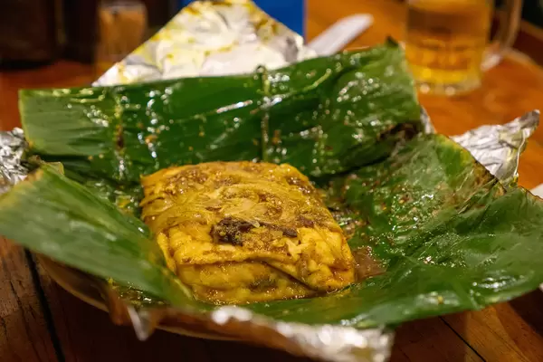 Close Up Food Photo of Steamed Tofu with Mushrooms, Onions and Tomatoes in a Banana Leaf in a Vegan Restaurant