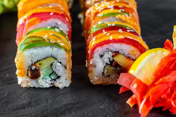 Close Up Food Photo of Sushi Rolls with Cheese and Salmon on Dark Plate with Ginger and Lemon
