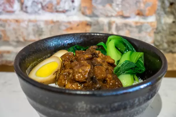 Close Up Food Photo of Taiwanese Braised Pork with Duck Egg, Bok Choy and White Rice in a Black Ceramic Bowl
