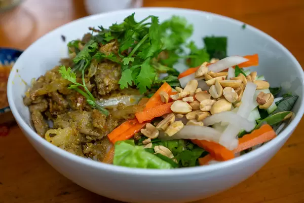 Close Up Food Photo of Vietnamese Dish Bun Thit Xao with Stir Fried Pork, Rice Vermicelli, Pickles, Peanuts and Herbs in a Restaurant