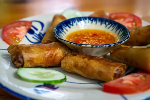 Close Up Food Photo of Vietnamese Fried Spring Rolls with Pork and Vegetables and a Fish Sauce Dip with Chili on a Ceramic Plate served at a Restaurant