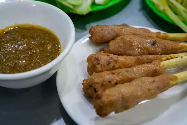 Close Up Food Photo of Vietnamese Grilled Pork Skewers Nem Nuong with Shrimp Paste Sauce at a Street Food Restaurant in Vietnam