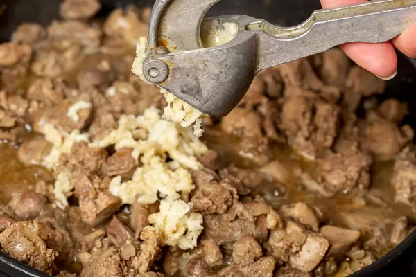 Close-up, garlic press chopping garlic
