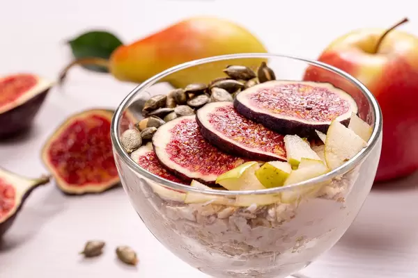 Close-up glass bowl of oatmeal with pieces of figs, pears, yogurt and pumpkin seeds (Flip 2019)