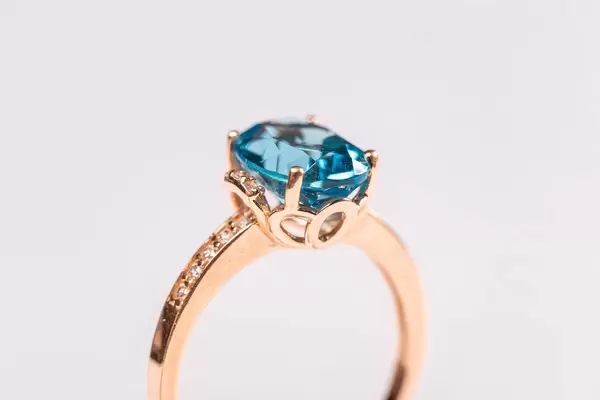 Close-up, golden ring with blue topaz on white