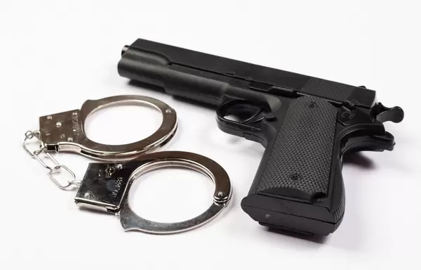 Close up gun and handcuffs isolated on white