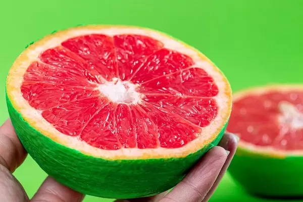 Close-up, half of fresh ripe grapefruit in a female hand
