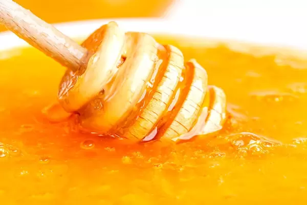 Close-up, honey dipper in sweet liquid honey