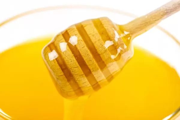 Close-up, honey dipper on the background of fresh bee honey