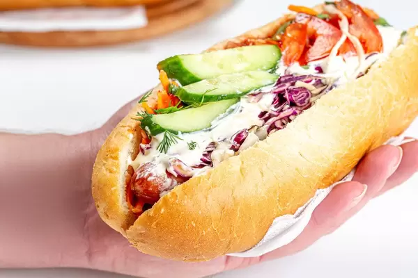 Close-up, hot dog with sausages and vegetables in hand