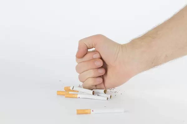 Close-up man hand crushing a pile of cigarettes