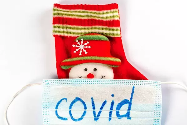 Close-up, mask with the inscription covid and christmas sock with snowman