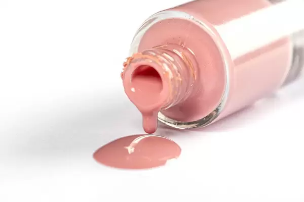 Close-up, nail polish spills over white backdrop