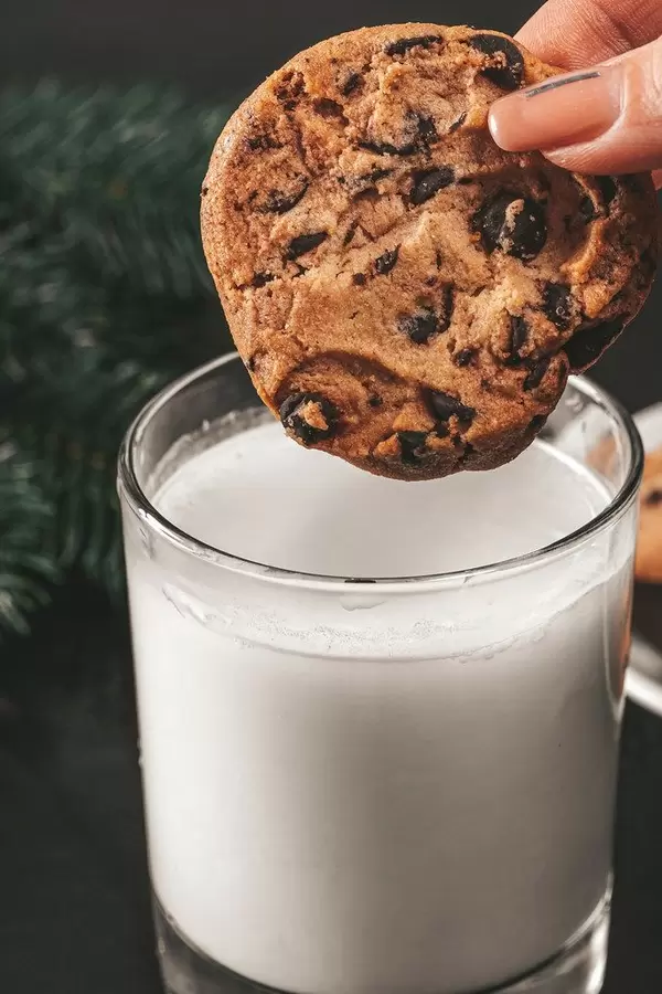Close up of a cookie with pieces of chocolate dipped in a glass of milk (Flip 2019)