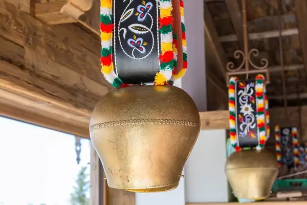 Close-up of a cow bell with colourful ribbon hanging from the ceiling: typical Alpine decoration in Austria
